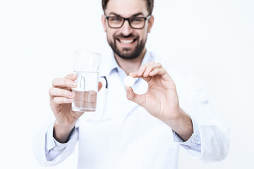 The doctor in the white coat is holding medicine.