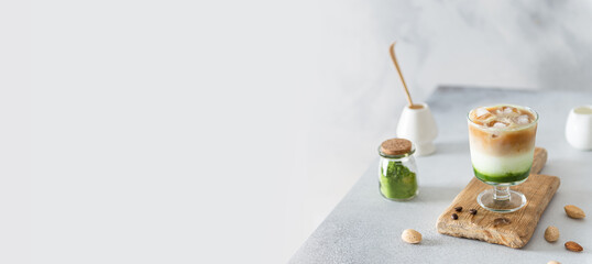 Obraz na płótnie Canvas Matcha green tea espresso banner. Matcha green tea with milk, ice and coffee on a wooden board. Layered matcha drink. Fresh summer drink. Side view, copy space. Bar, cafe, coffee house banner