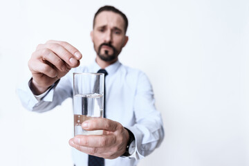 A man in a shirt stands and drinks pills for pain.