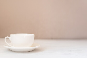White cup on white wooden table. Coffee or tea mockup with copy space