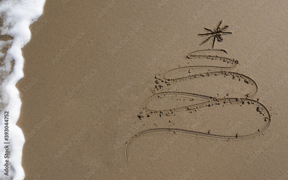 Wall mural christmas tree drawn in sand at the beach.