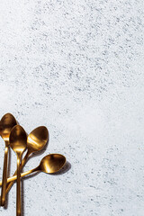 Empty golden dessert spoons on gray background, copy space, top view. Eating food concept. Empty cutlery background.