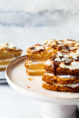 Vegan cake on cake plate. Homemade carrot cake with white cream, caramel and nuts.