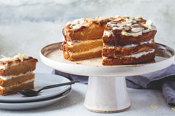 Vegan cake on cake plate. Homemade carrot cake with white cream, caramel and nuts.