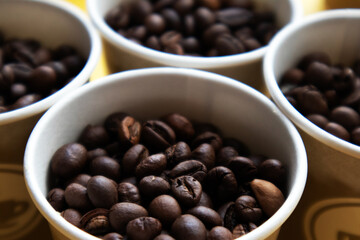 The tops of few cardboard cups full of roasted coffee beans