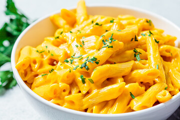 Mac and cheese in white bowl, gray background. Cheese pasta in bowl.
