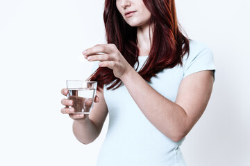 Woman pours medicine into a glass of water. 