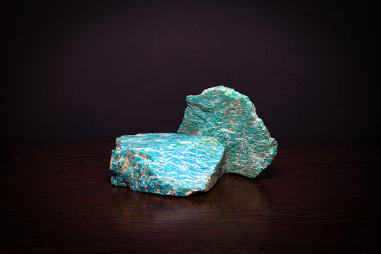 Two pieces of beautiful bright semiprecious mineral amazonite lying on a wooden surface