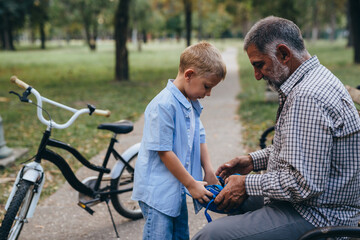 Fototapeta premium boy preparing to ride bike with his grandfather in public park
