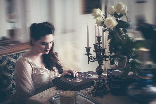 Young woman looks at a photo album. Vintage style, retro interior.