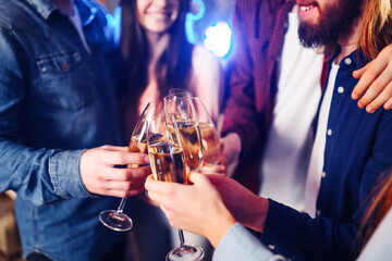 Happy group of young friends touching the glasses with each other. Friends celebrating winter holidays in luxury nightclub together. Relax, clinking wineglass, surprise.