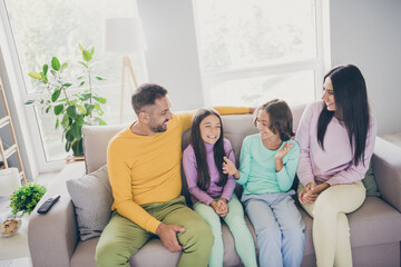 Photo of full family four people sit couch son hands daughter smile wear colorful pullover in...