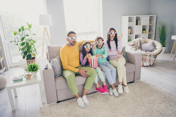 Photo of full family four members sit sofa eat popcorn watch film shock wear 3d specs colorful jumper pants in living room indoors