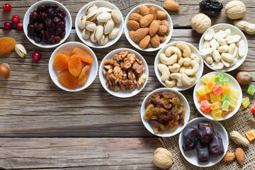 Mix of nuts and dried fruits in small bowls on wooden boards. Healthy and tasty snack 