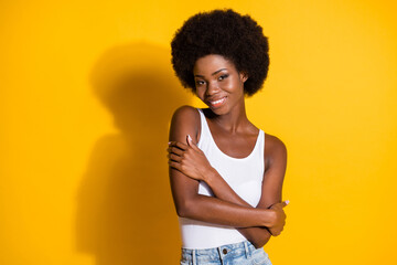 Photo of tender black young girl embrace herself wear white tank-top isolated yellow color...