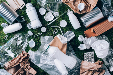 Plastic waste, food packaging, trash collection on green moss background after picnic in forest. Plastic free. Top view. Copy space. Recycling plastic. Environmental pollution, ecology concept. - 393049100