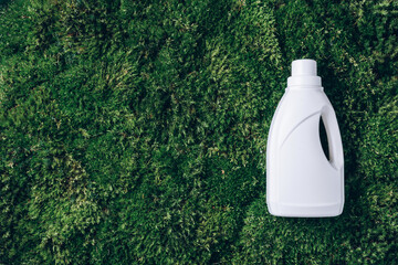 White plastic bottle of cleaning product, household chemicals or liquid laundry detergent on green...