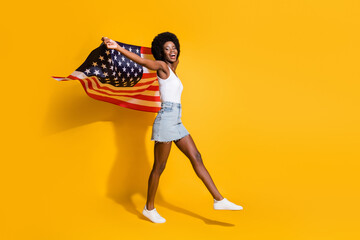 Full length body size view of thin cheerful wavy-haired girl holding us flag going shadow isolated...