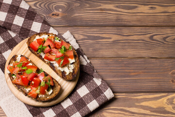 Bruschetta with tomatoes, mozzarella cheese and basil on a black background. Traditional italian appetizer or snack, antipasto. Top view with copy space. Flat lay