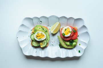 healthy vegetarian breakfast, avocado toast with cucumber, eggs, tomato and greean salad on wholegrain bread