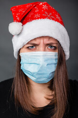 Close-up portrait of a woman wearing a medical, disposable mask and a Christmas red hat.