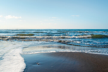 Beautiful seascape. Wild beach of the Sea of Okhotsk, Sakhalin island, Russia. Endless sea and clear blue sky. Waves are washed up to the shore. Natural background with copy space. Beauty in nature.
