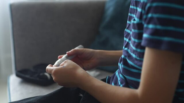 A diabetic child takes a blood sample using a Lancet pen at home.