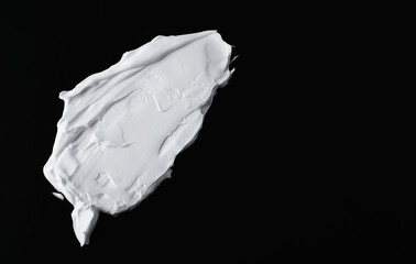 White smear of cream on black background