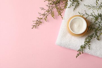 Obraz na płótnie Canvas Towel with jar of cosmetic cream on pink background