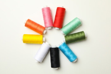 Color sewing threads on white background, top view