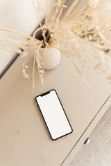 Blank screen smart phone on beige pastel table. Flat lay, top view. Copy space mockup template.
