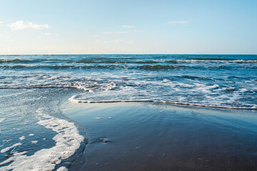 Beautiful seascape. Wild beach of the Sea of Okhotsk, Sakhalin island, Russia. Endless sea and clear blue sky. Waves are washed up to the shore. Beauty in nature. Natural background with copy space.
