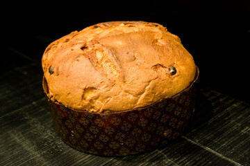 the typical Italian Christmas sweet panettone on black wood background