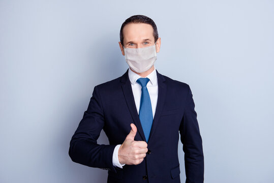 Photo portrait businessman showing thumb up wearing white face mask isolated on grey colored background
