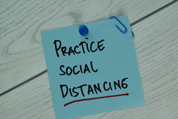 Practice Social Distancing write on sticky note isolated on Wooden Table.