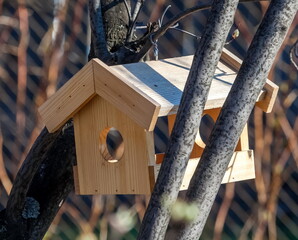 Wooden bird feeder on the background of tree branches in spring