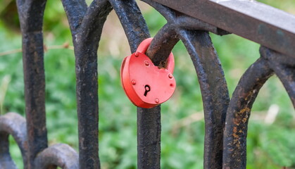 Castle on the metal railing of the bridge over the river close-up against the background of greenery