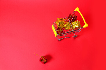 A boxes with a ribbon in a shopping trolley. Concept - buying a gift. on red background concept of...