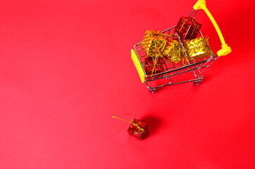 A boxes with a ribbon in a shopping trolley. Concept - buying a gift. on red background concept of...