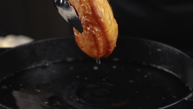 cooking one berliner or doughnut on a frying pan close-up. fat and oil boiling, hot temperature