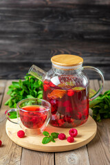 Herbal tea with berries, raspberries, mint leaves and hibiscus flowers in glass teapot and cup on wooden table Medicine for cold Vitamin drink Rustic style - 393061333