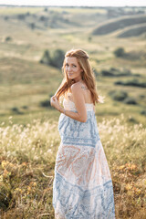Fototapeta na wymiar Touching portrait of charming pregnant red hair woman relaxing in the summer meadow