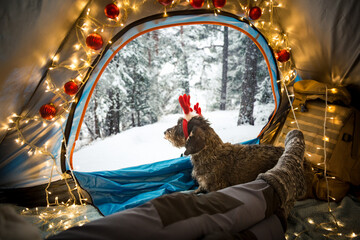 A man lying in a tent decorated with Christmas lights wearing warm wooden socks. Beautiful winter...