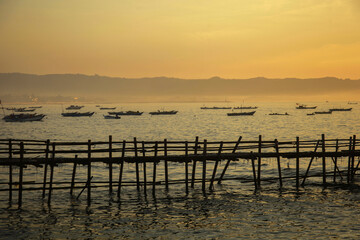 Fototapeta premium Sunrise view from sea with beautiful twilight sky, fishing boats preparing the trap with mountain in background.