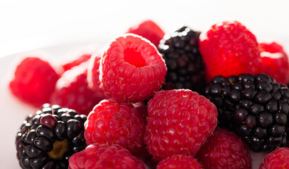 handful of raspberry and blackberry berries on white background