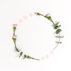 Wreath made of confetti, flowers and eucalyptus on a white background. Festive frame with copy space.