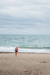 Obraz premium A woman going into the cold sea with her bathing suit on November 9-th 2020. Autumn winter season on the beach.