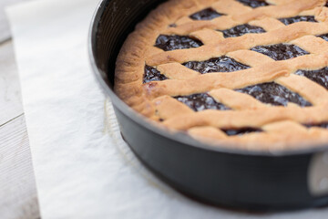 Coronavirus quarantine, homemade dessert - cake with cherry jam freshly baked and placed on parchment paper on a wooden table.