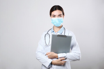 Young woman doctor in a protective mask on a light background
