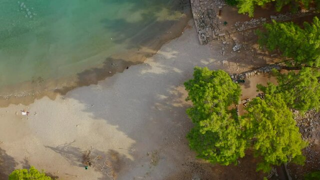 A beautiful turquoise tropical sea and forest, coastline and ancient city ruins, a blue sea and sea waves. Nice beach and trees. Mediterranean, camera seen from above, drone camera.